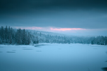 Wall Mural - Wonderful natural morning scene of a frozen lake in the white winter mountains with dramatic clouds and weather. Oderteich, Harz Mountains National Park in Germany