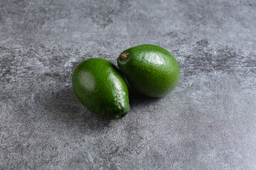 Wall Mural - two green avocados lie on an artificial stone board. diet food. green vegetable.