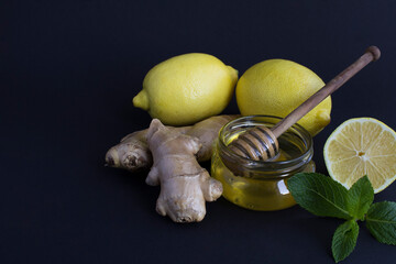 Wall Mural - Close-up on lemon, ginger and honey on the black  background. Ingredients for tea. Copy space.