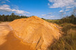 Large pile of industrial sand, stockpiled and prepared for use in construction and road construction, against a backdrop of blue sky and green forest. Top view