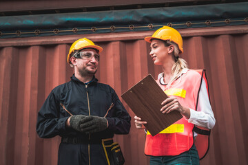 Industrial worker works with co-worker at overseas shipping container yard . Logistics supply chain management and international goods export concept .