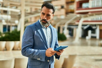 Wall Mural - Middle age businessman with serious expression using touchpad at the city.