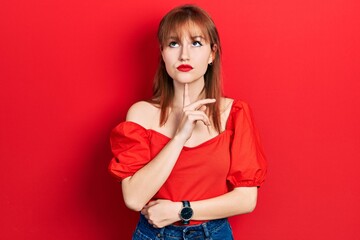 Canvas Print - Redhead young woman wearing casual red t shirt thinking concentrated about doubt with finger on chin and looking up wondering