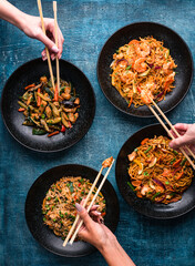 Wall Mural - hand with chopsticks, eating asian food, top view. Chinese and vietnamese cuisine set.