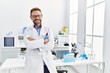 © Krakenimages.com - Middle age hispanic man wearing scientist uniform with arms crossed gesture at laboratory
