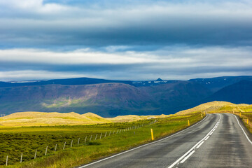 summer road trip on an open high way in Route 1 in Iceland with dramatic mountain landscape on the background.