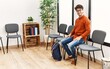 © Krakenimages.com - Young hispanic man smiling confident sitting on chair at waiting room
