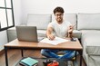 © Krakenimages.com - Hispanic man doing papers at home pointing aside worried and nervous with forefinger, concerned and surprised expression