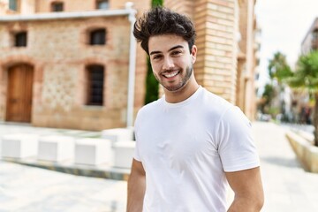 Young hispanic man smiling happy standing at the city.