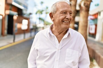 Senior man with grey hair standing happy outdoors on a sunny day. Smiling happy at 70s for retirement.