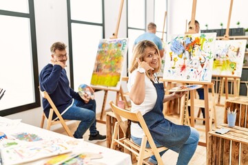 Wall Mural - Group of middle age artist at art studio smiling doing phone gesture with hand and fingers like talking on the telephone. communicating concepts.