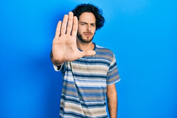 Sticker - Handsome hispanic man wearing casual clothes over pink background doing stop sing with palm of the hand. warning expression with negative and serious gesture on the face.