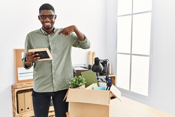 Poster - Young african american businessman unboxing box at the office looking confident with smile on face, pointing oneself with fingers proud and happy.