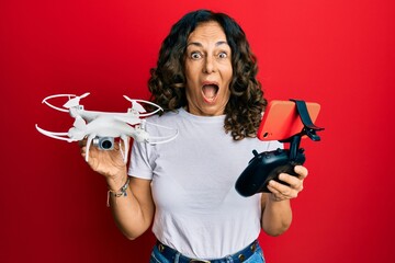 Sticker - Middle age hispanic woman using drone celebrating crazy and amazed for success with open eyes screaming excited.