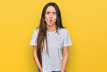 Sticker - Young hispanic girl wearing casual white t shirt making fish face with lips, crazy and comical gesture. funny expression.