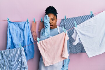 Wall Mural - African american woman with braided hair washing clothes at clothesline yawning tired covering half face, eye and mouth with hand. face hurts in pain.