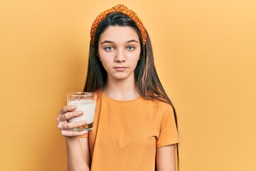 Sticker - Young brunette girl drinking a glass of milk thinking attitude and sober expression looking self confident