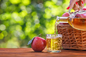 Wall Mural - apple cider or juice pouring in glass from bottle