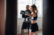 © romankosolapov - Beautiful woman boxing combat bag with sport trainer together. Girl boxer exercising box punch with personal coach.