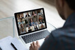 © fizkes - View over businessman shoulder group video call on laptop screen, diverse colleagues business partners chatting online, engaged in internet conference, meeting by webcam, distance work concept