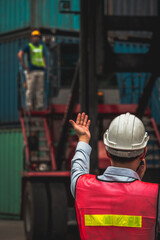 Industrial worker works with co-worker at overseas shipping container yard . Logistics supply chain management and international goods export concept .