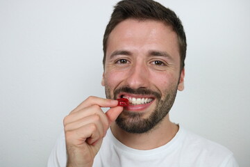 Young caucasian man eating red gummy candy 