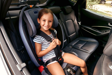 Wall Mural - Child cute girl in a car seat is protected by seat belts. Leisure, travel, tourism.Protection during the trip in the car.