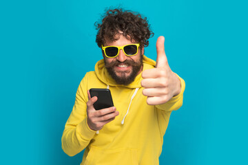 Wall Mural - happy young guy in yellow hoodie making thumbs up gesture