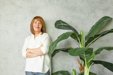 Cheerful middle aged woman with redhead hair with green plant