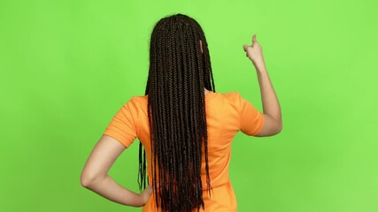 Poster - Teenager girl with braids pointing back with the index finger over isolated background. Green screen chroma key