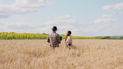 Wall Mural - Large wheat field two farmers lady and man multiethnic analysing together from the laptop the result of harvest from this year