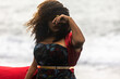 African American woman with afro hair is wearing a fashionable cosplay red dress while walking along the black sand beach. the independent woman is bravely entering a dark fantasy world.