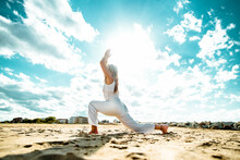Senior Woman Doing Yoga Exercise Tree Pose At Beach - Calm And Meditation Concept	
