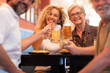 © simona - Happy cheerful family having fun and clinking beer glasses together while sitting at table in restaurant. Portrait of family toasting beer glasses and celebrating at restaurant