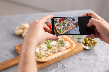 Wall Mural - Chef takes pictures of the cooked of italian pizza with parma ham on smartphone. Photographing food and social networks concept.