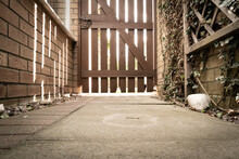 Ground Level View Of A Locked Side Gate. The Gate Leads To A Private, Residential Driveway. To The Left Is A Brick Wall, Part Of A Conservatory.