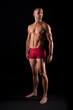 © Iván Moreno - Studio photo of strong male in pants standing, black background