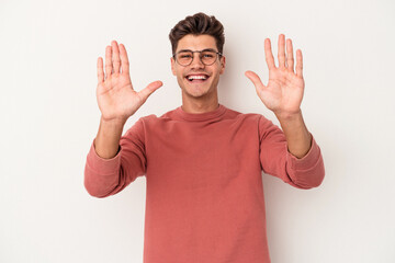 Young caucasian man isolated on white background showing number ten with hands.