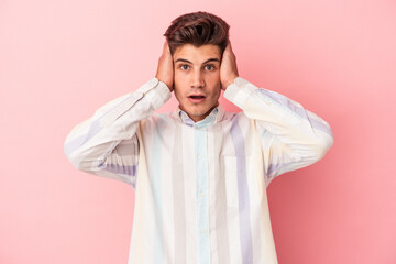 Young caucasian man isolated on pink background being shocked, she has remembered important meeting.