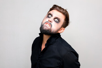 Wall Mural - a bearded man with undead-style makeup on Halloween looks with big eyes at the camera