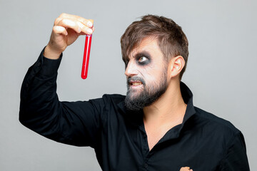 Wall Mural - a bearded man with undead makeup for Halloween holds test tubes in which red liquid