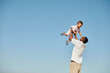 © Seventyfour - Minimal portrait of happy African-American father playing with cute baby and throwing him against blue sky, copy space