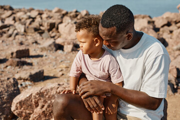 Wall Mural - Portrait of loving African-American father playing with cute son on beach, copy space