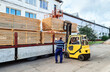 © Zhanna - Loading lumber on a truck, a man controls the loading