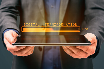 Poster - Businessman hand holding tablet computer with abstract glowing loading bar on gray wall background. Digital transformation, internet, progress and technology concept.