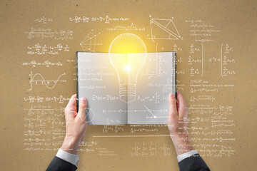Wall Mural - Hand holding open book with abstract light bulb sketch with mathematical formulas on light wall background. Intelligence, idea, solution, science and innovation concept.