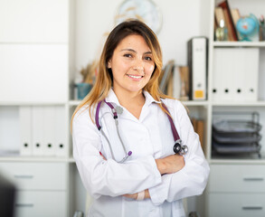 Wall Mural - Young mexican female medic in uniform standing in doctor's office