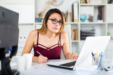 Young colombian woman in glasses working with laptop at the office table