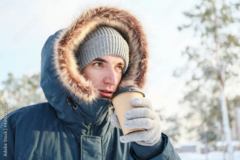 Young man with cup of hot tea on snowy day