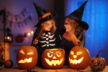 Happy Family Mother And Little Girl Daughter In Witch Costumes Celebrating Halloween At Home